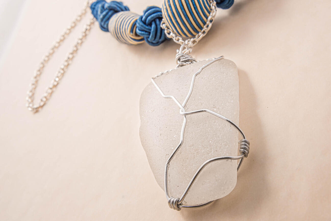 Large frosted white sea glass pendant from a stone beach featuring a unique pitted texture, hand-wrapped in intricate silver wire.